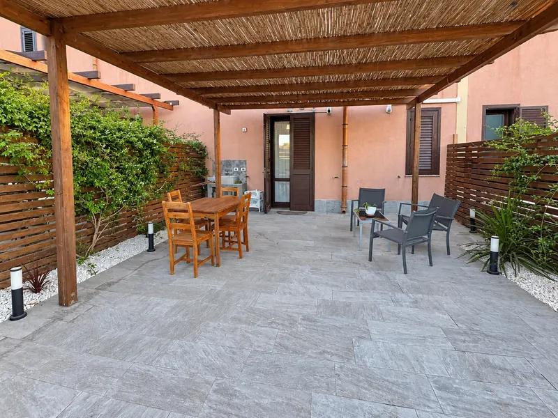 La terrazza coperta dal pergolato, col tavolo da pranzo in legno e il salottino da esterno